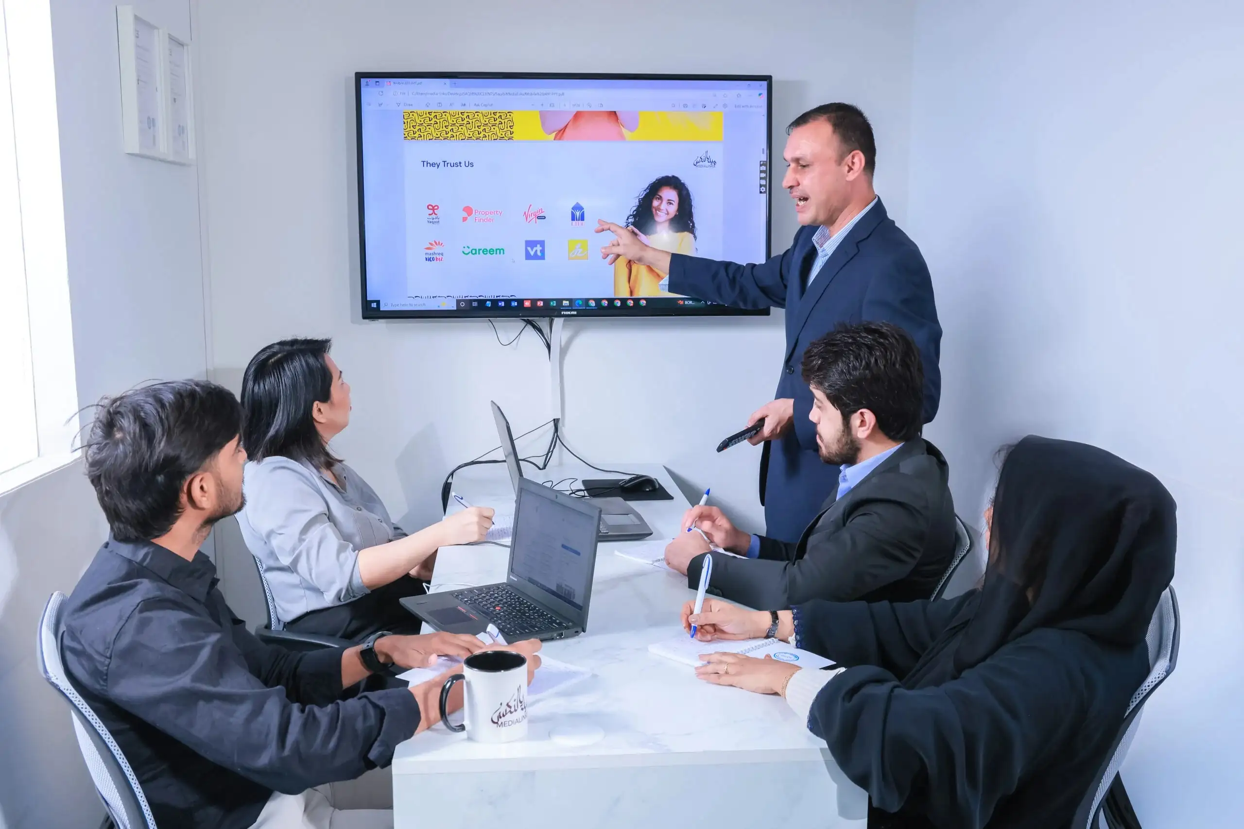 Team of professionals collaborating in a modern office meeting with laptops, discussing ideas and strategy for business growth.