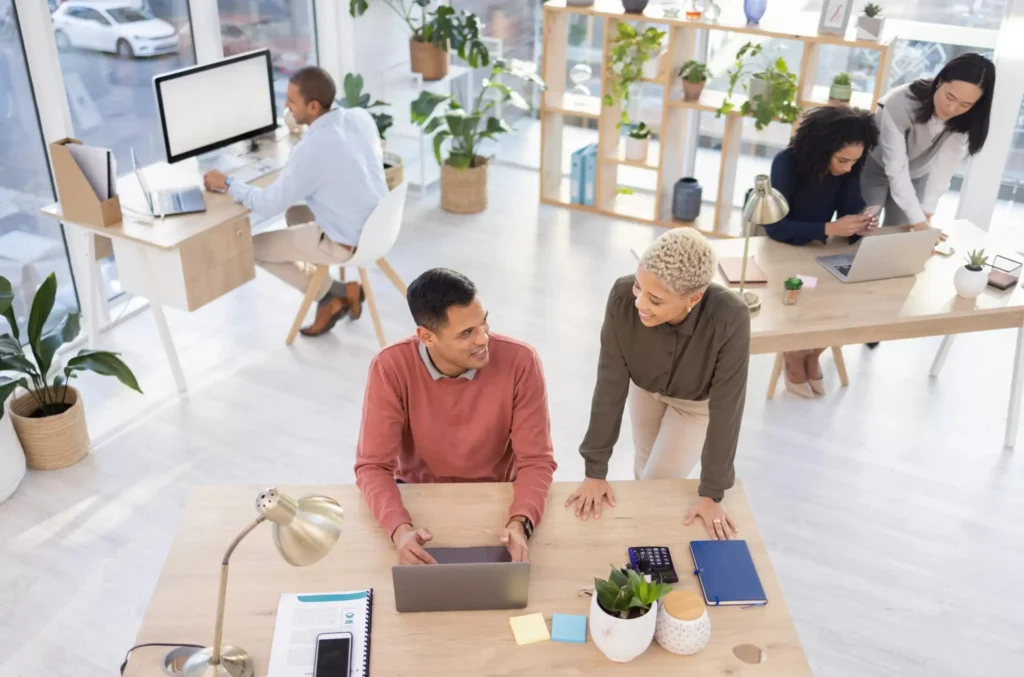Team of professionals collaborating in a modern office meeting with laptops, discussing ideas and strategy for business growth.