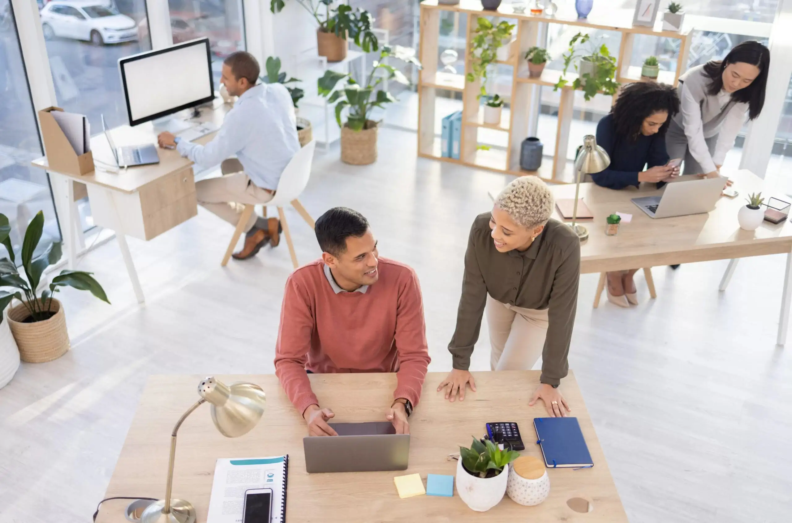 Team of professionals collaborating in a modern office meeting with laptops, discussing ideas and strategy for business growth.