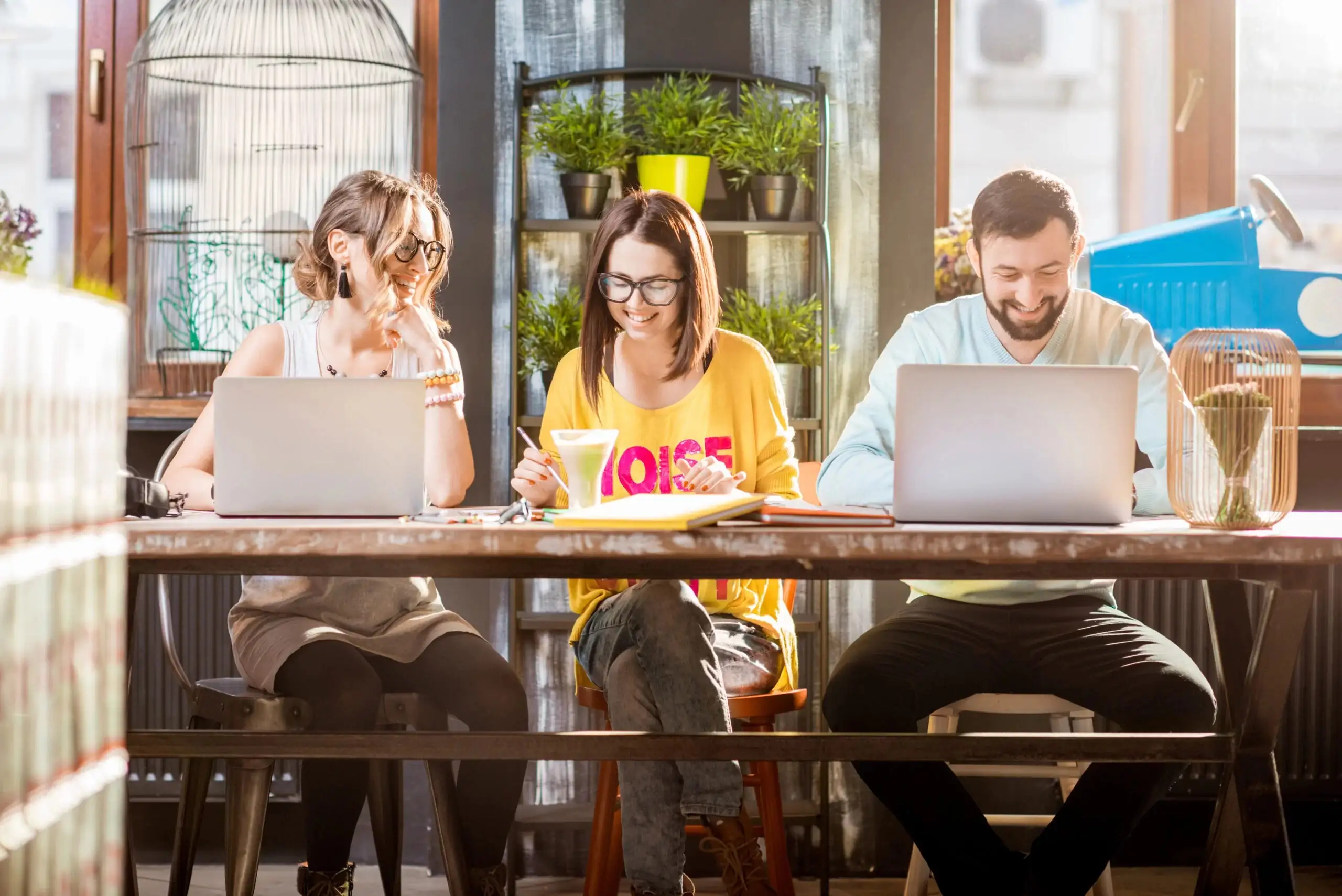 Team of professionals collaborating in a modern office meeting with laptops, discussing ideas and strategy for business growth.