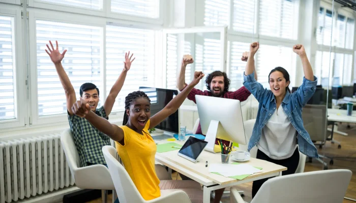 Portrait of business executives raising arms in office